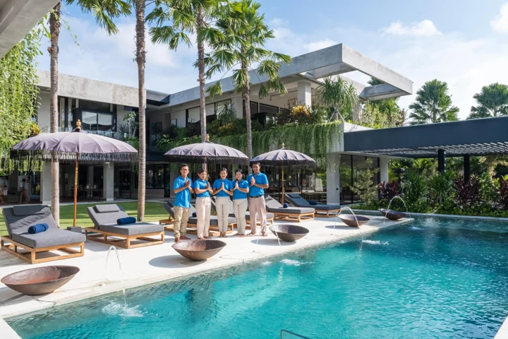 Sunlit swimming pool, loungers and tropical palms at The V House