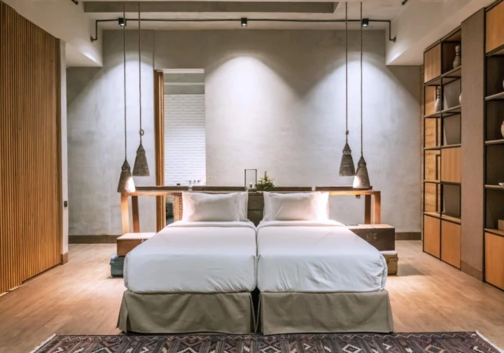 Bedroom with a white bed, warm wood and pendant lamps