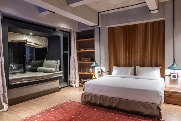 Timber-lined bedroom with a large bed and garden-facing window seat