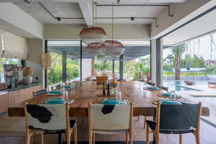 Long indoor dining table surrounded by open glass doors