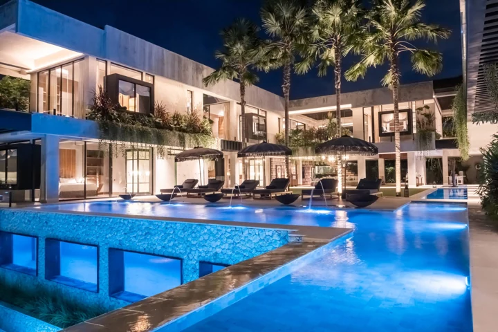 Illuminated villa and swimming pool beneath the evening sky