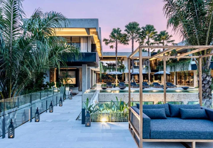 Villa and terraces at dusk with palms against a pink sky