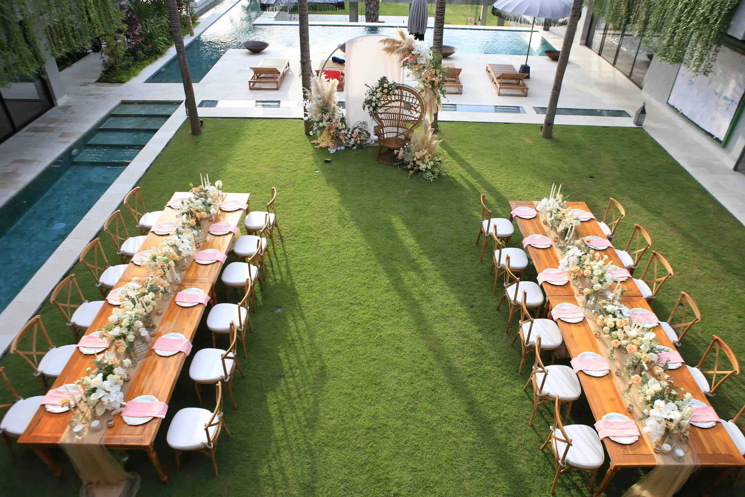 Tables dressed for a private reception in the garden beside the pools
